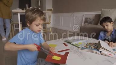 专心致志的5岁男孩用剪刀热情地<strong>剪纸</strong>。 伸出舌头。 集中5岁男孩<strong>剪纸</strong>